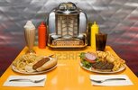 7060194-50er-jahre-stil-diner-tabelle-mit-malz-cola-hot-dog-juke-box-hamburger--istock-der-song-.jpg